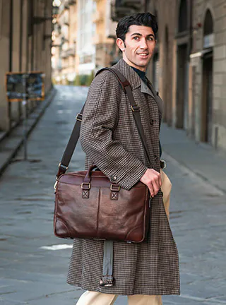 Man wearing pea coat looking to the right with sleek black leather bag hanging over shoulder